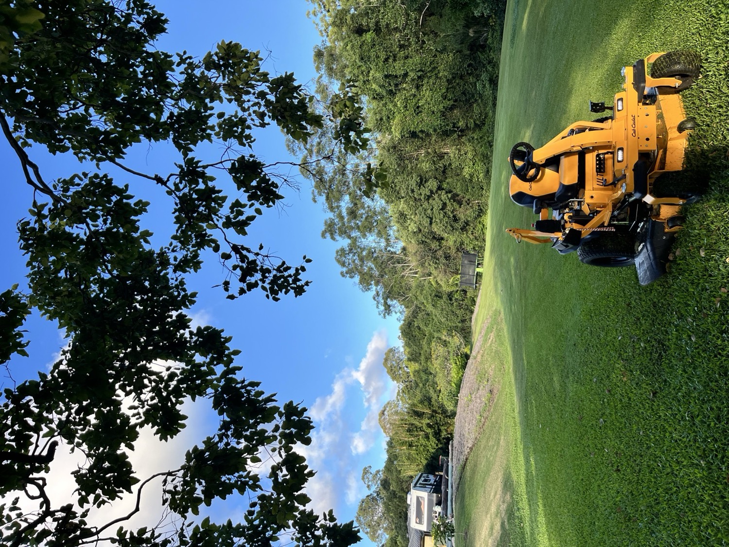 A Greencare Noosa ride-on mower on a wide, freshly cut lawn under open sky